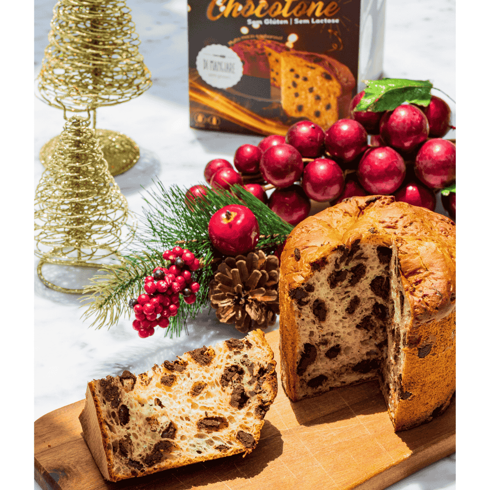 Chocotone sem glúten e sem leite Di Mangiare, 500 g – Chocotone cortado e uma fatia em tábua de madeira, com caixa e enfeites natalinos ao fundo